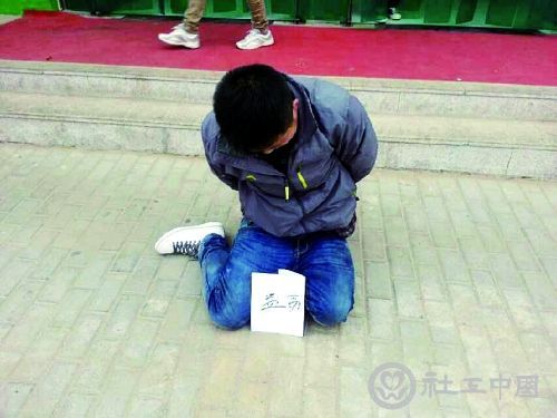 小偷被抓后，双手背在身后，跪坐在学校的餐厅门口