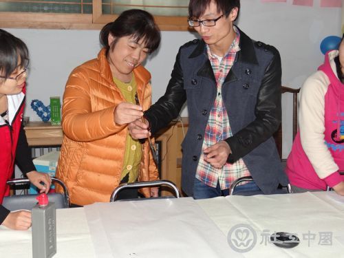 书法志愿者在教聋人阿姨握笔的姿势