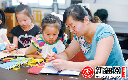 7月10日，在乌鲁木齐幸福城市花园社区，社工金艳红在教小朋友用废旧台历做笔记本。