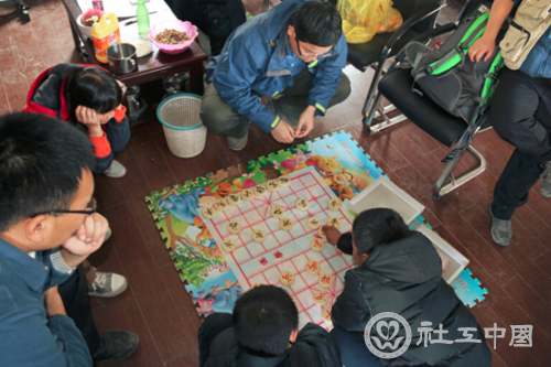 （图注：服务队队员与学生下象棋，在丰富校园生活的同时带来欢声笑语）