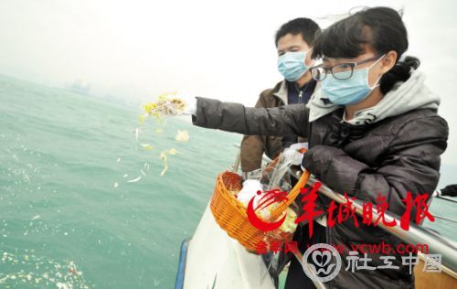 家属将亲人的骨灰伴花撒向大海
